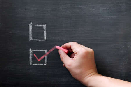Check boxes with a hand writing a tick with chalk on a smudged blackboard