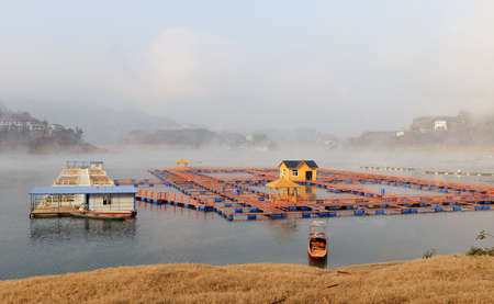 Landscape of floating house on a lake in a foggy morningの写真素材