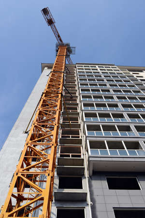 High-rise building under construction, with cranes against blue sky の写真素材