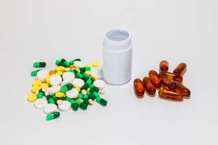 Closeup of medicine pills, capsules and antibiotic medicine next to plastic bottle isolated. On white background.の写真素材