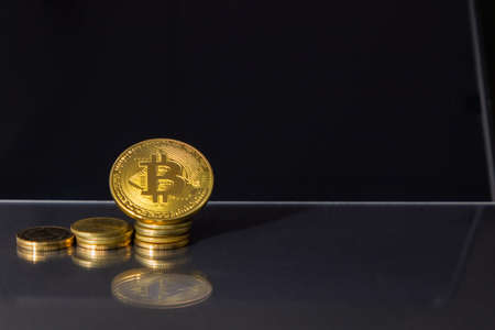 Close up of Golden bitcoin in front of stock chart in tablets on the glass floor. Dark, bokeh,...