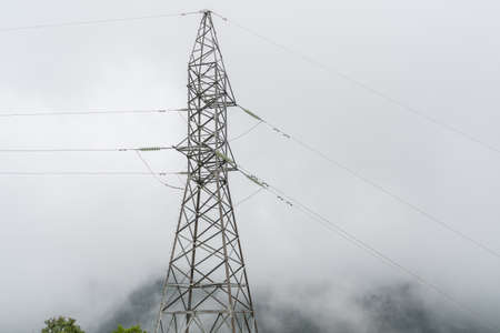 High voltage pole towers on the mountain in the fog and mist on forest. White background