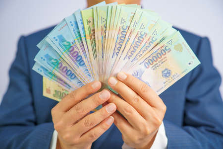 Money in Vietnam hold on hand business man wearing a blue suit (Socialist Republic Of Vietnam), Dong, VND, Pay, exchange money vietnamese on white background.の写真素材