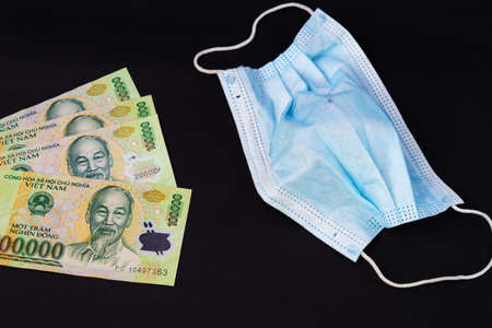 Money in Vietnam Dong, VND vietnamese mask health guard face earloop surgical for doctor, people Take care health and protect coronavirus disease COVID-19 and SMOG smoke fog PM2.5 on black background.の写真素材