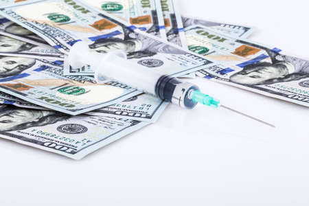 
Hypodermic needle on a stack of money. Medical and health concept