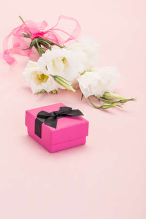 white flowers and gift box on pink