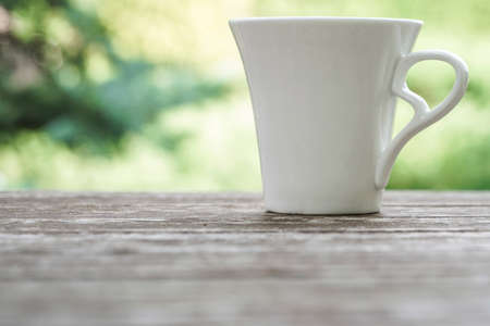 white coffee mug on a wooden table against green background bokehの写真素材