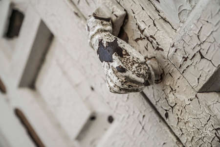 Hand shaped knocker on an old wooden doorの写真素材
