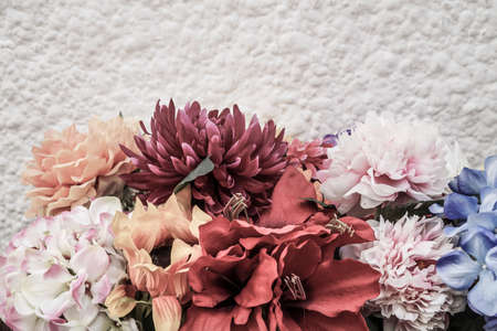 border with artificial flowers against white wall with copy spaceの写真素材