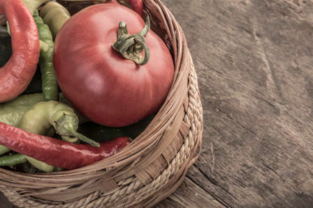 Some fresh vegetables in a basket on wooden tableの写真素材