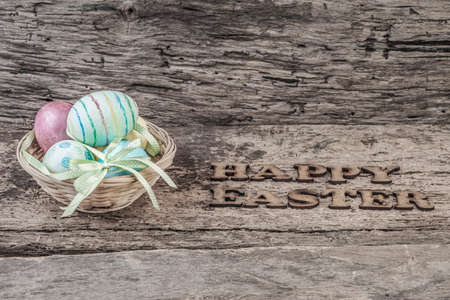 Colorful easter eggs in a basket on wooden backgroundの写真素材
