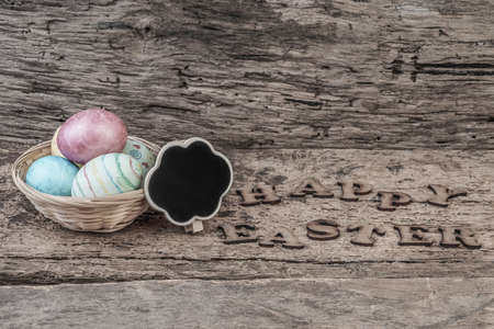 Easter template with colorful eggs and an empty chalkboard on wooden backgroundの写真素材