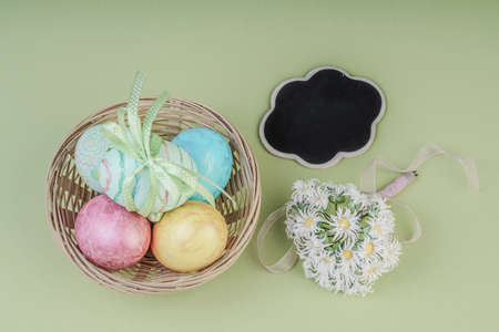 Colorful easter eggs and an empty chalkboard on green background
