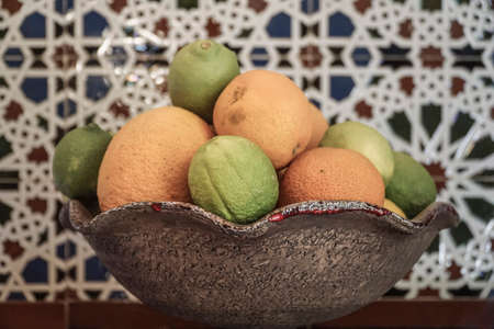 orange and limes in a bowl on tableの写真素材