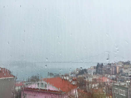 Rain drops on window pane against buildings and Bosporus in Istanbul, Turkey