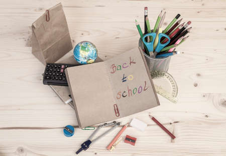 Back to school template with school stationeries and lunch bag on wooden table