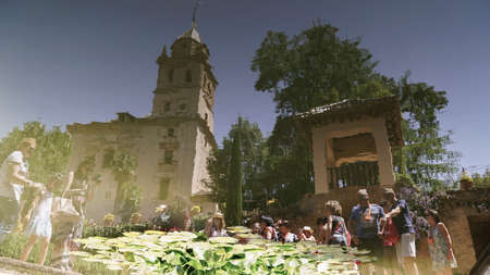 Reflection of visitors and Santa Maria Church on pond in Jardines del Partal gardens at the Alhambra Palace in Granada, Andalusia in Spain.のeditorial素材