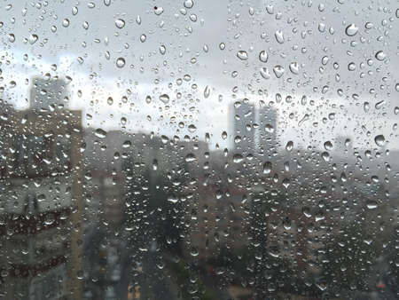 rain drops on windowpane against buildings as a backgroundの写真素材