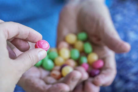 A young hand picks a hard candy from palm of a senior personの写真素材