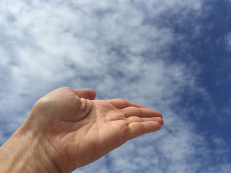 An empty open hand palm against blue skyの写真素材