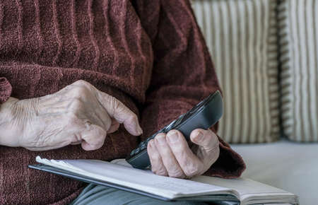 closeup wrinkled hand holding a phoneの写真素材