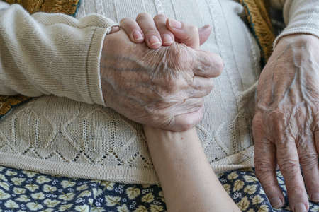 closeup wrinkled hand holding a younger handの写真素材