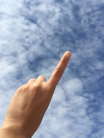 A female hand touching or pointing to something against blue skyの写真素材
