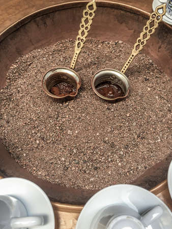 Close up view of traditional turkish coffee preperation on hot golden sand.