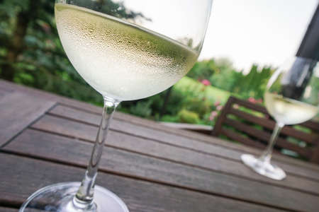 Pair of wine glasses on wooden table at garden in summer