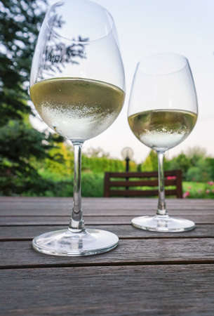 Pair of wine glasses on wooden table at garden in summerの写真素材