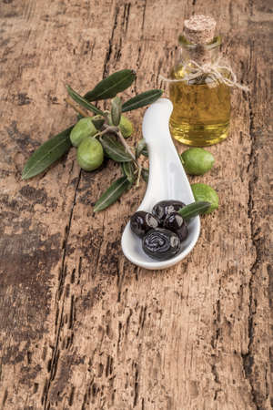 Green and black olives and olive oil on wooden tableの写真素材