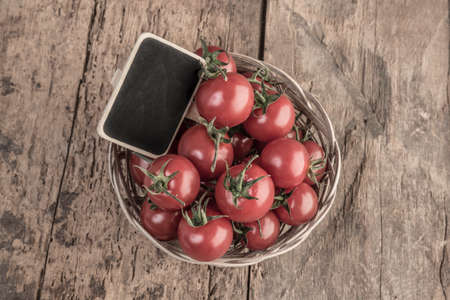 An empty chalkboard on ripe cherry tomatoes on wooden tableの写真素材