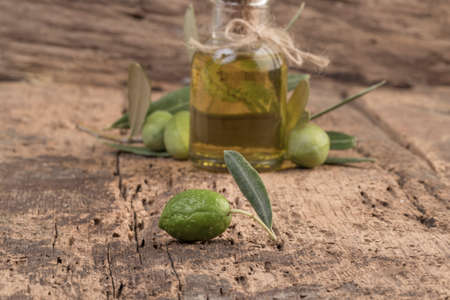 Unripe green olives and olive oil on wooden tableの写真素材