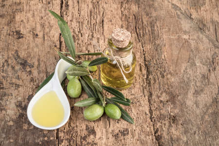 Unripe green olives and olive oil on wooden tableの写真素材