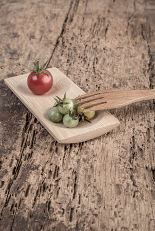 Ripe and unripe cherry tomatoes on wooden tableの写真素材
