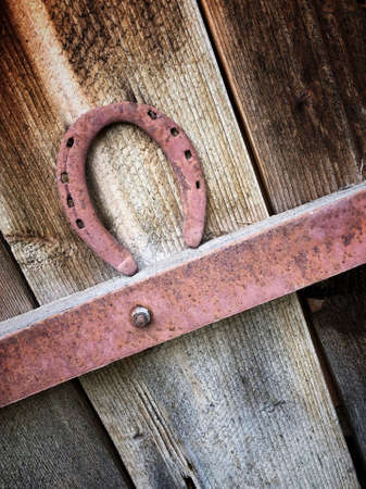 hanged rusty horseshoe on a wooden door for good luckの写真素材