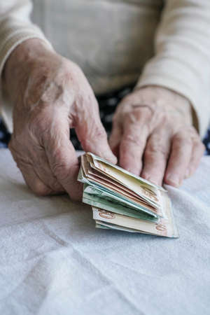 Wrinkled hands of a senior person counting turkish lira banknotesの写真素材