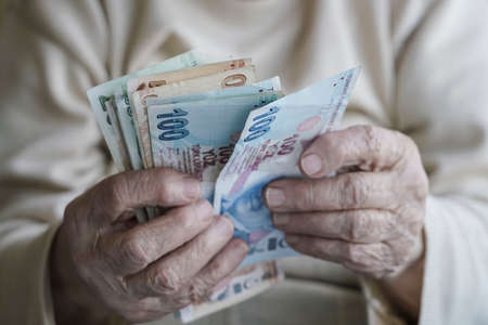 Wrinkled hands of a senior person counting turkish lira banknotes