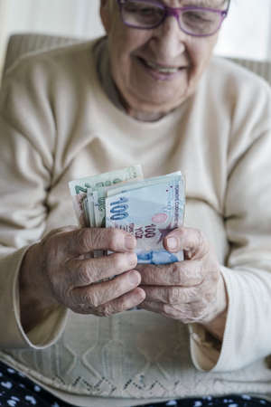 Wrinkled hands of a happy senior woman counting turkish lira banknotesの写真素材
