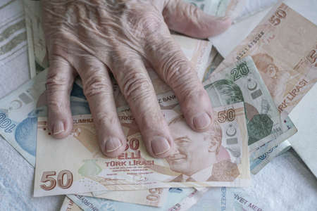 Wrinkled hand of a senior person on turkish lira banknotes