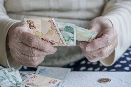 Wrinkled hand of a senior person counting turkish lira banknotesの写真素材