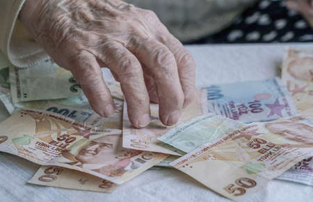 Wrinkled hands of a senior person counting turkish lira banknotes
