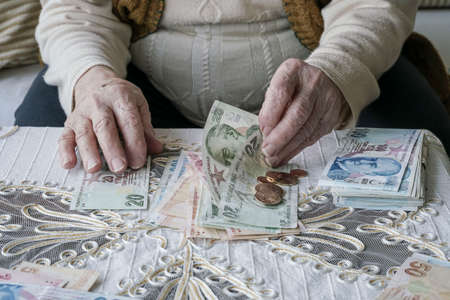 Closeup wrinkled hands of a senior woman counting Turkish Lira banknotes