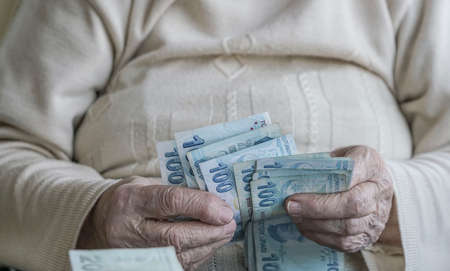 Wrinkled hands of a senior person counting turkish lira banknotes