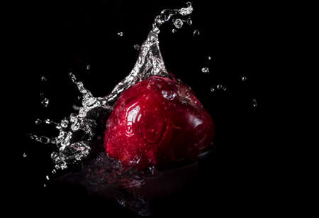 A red apple falling in water with splash on black backgroundの写真素材
