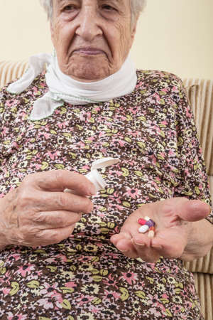 An ill senior woman holding pills on palmの写真素材