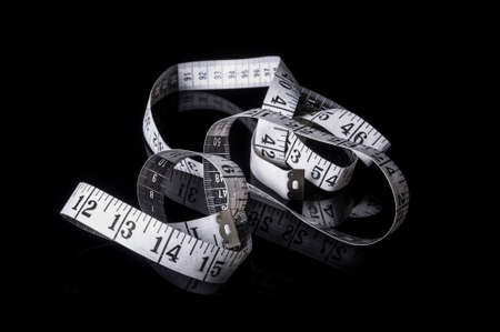 A white measuring tape on black background with reflectionの写真素材