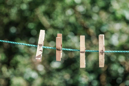 Some wooden clothes pegs hanged on rope at garden in spring