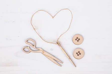 Template for tailors with needle and button figurines on wooden surface