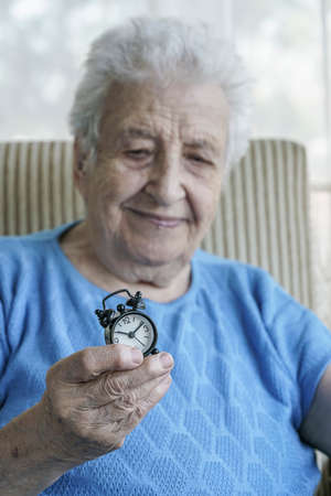 A happy senior woman holding a clock